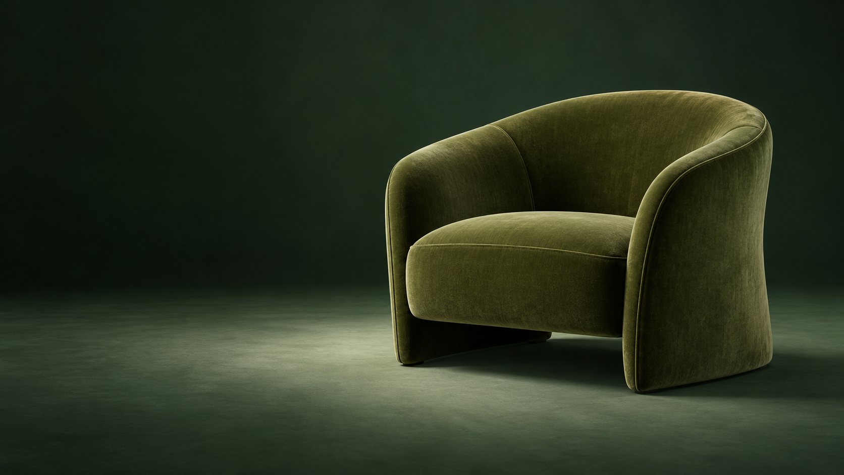 A deep green velvet accent chair in a pool of soft light