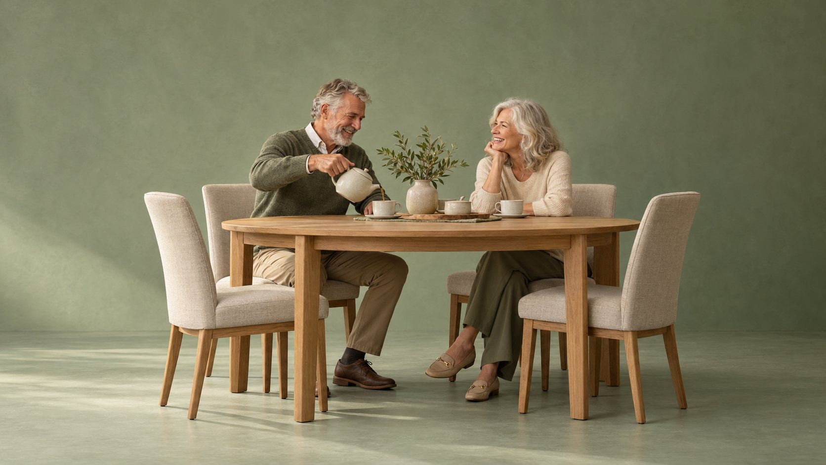 An older couple sharing tea at an oak dining table with upholstered chairs